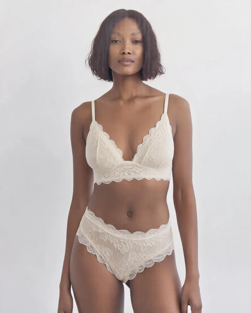 Celeste Lace Brief in Ivory, front view on the model: a mid-rise brief in scalloped stretch lace with a cotton gusset, matching the Celeste bralette
