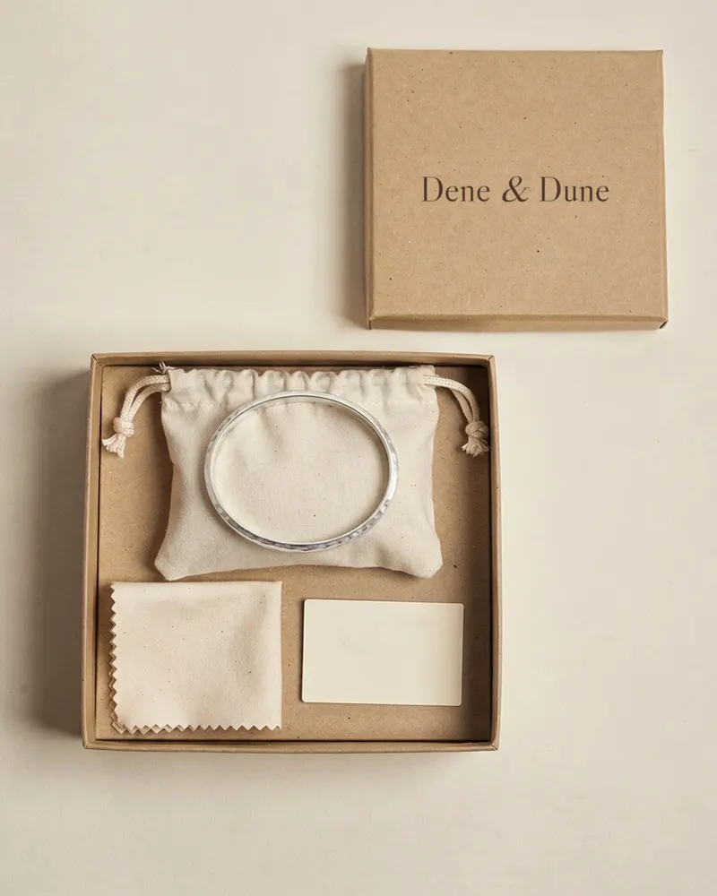 Hammered Oval Bangle in Recycled Silver in its Dene & Dune gift box with pouch and care card