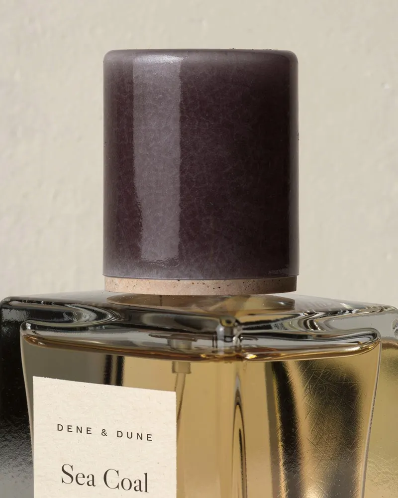 Close-up of the Sea Coal Eau de Parfum: hand-glazed stoneware cap in deep aubergine